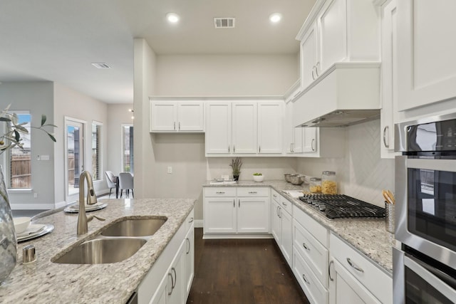 kitchen with stainless steel gas stovetop, white cabinetry, sink, and light stone counters