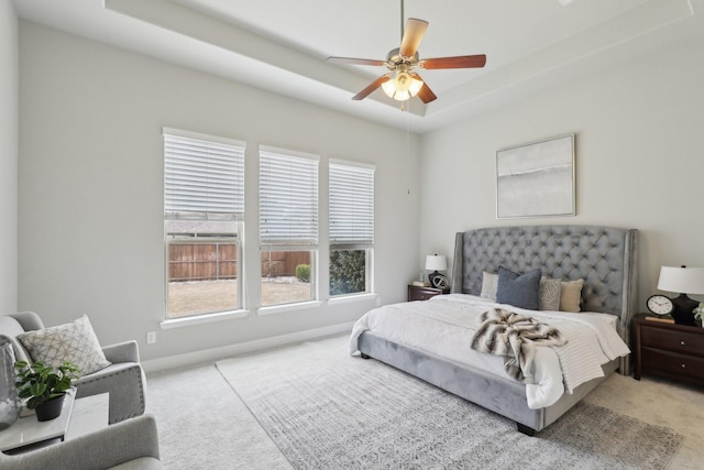 bedroom featuring a tray ceiling, light colored carpet, and ceiling fan