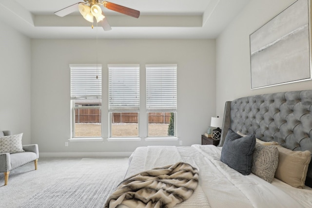 bedroom featuring a tray ceiling, carpet floors, and ceiling fan