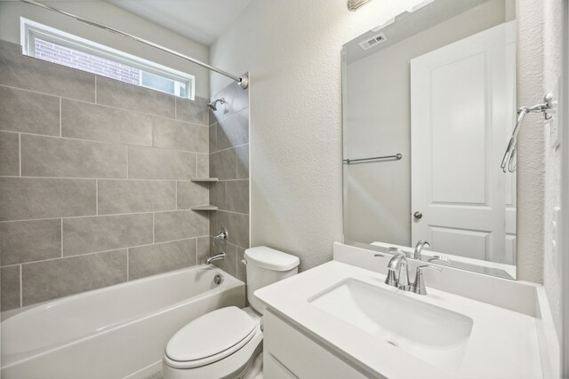 full bathroom featuring vanity, tiled shower / bath combo, and toilet