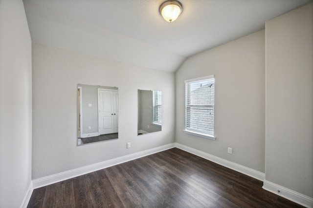 empty room featuring lofted ceiling and dark wood-type flooring