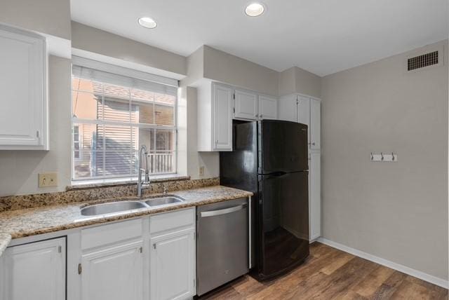 kitchen with hardwood / wood-style floors, black fridge, sink, stainless steel dishwasher, and white cabinetry