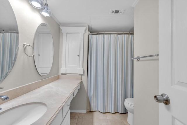 bathroom featuring tile patterned floors, vanity, ornamental molding, and toilet