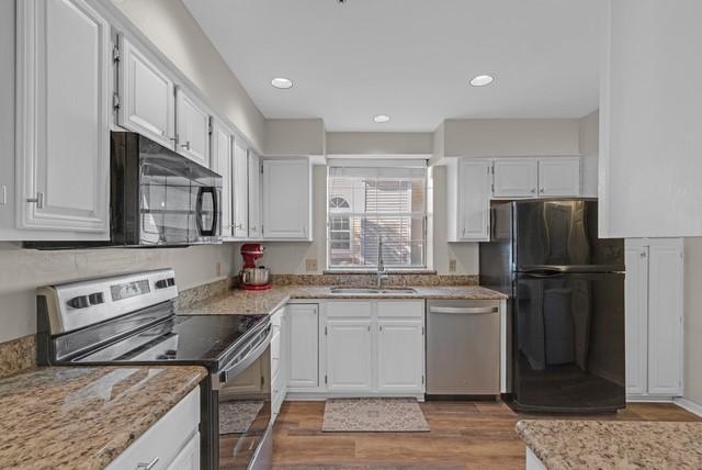 kitchen featuring black appliances, dark hardwood / wood-style floors, white cabinetry, and sink