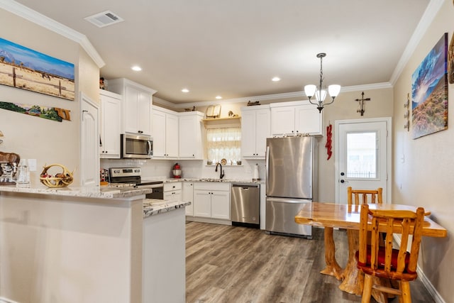 kitchen with light stone countertops, appliances with stainless steel finishes, sink, pendant lighting, and white cabinetry