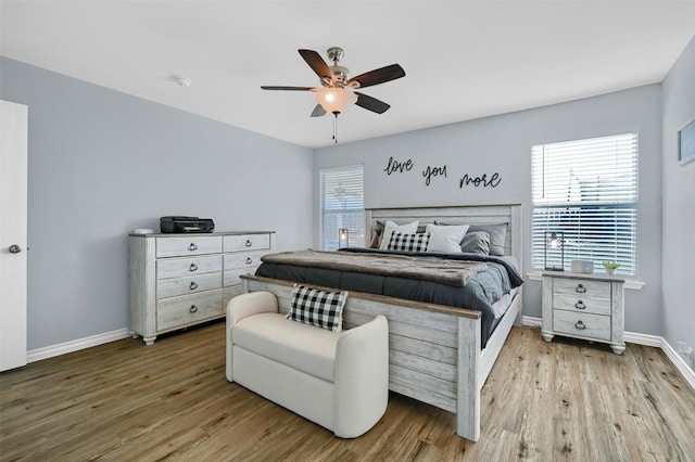 bedroom with multiple windows, light hardwood / wood-style floors, and ceiling fan