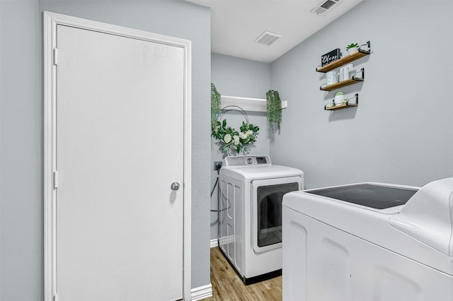 laundry area with light wood-type flooring and washer and clothes dryer