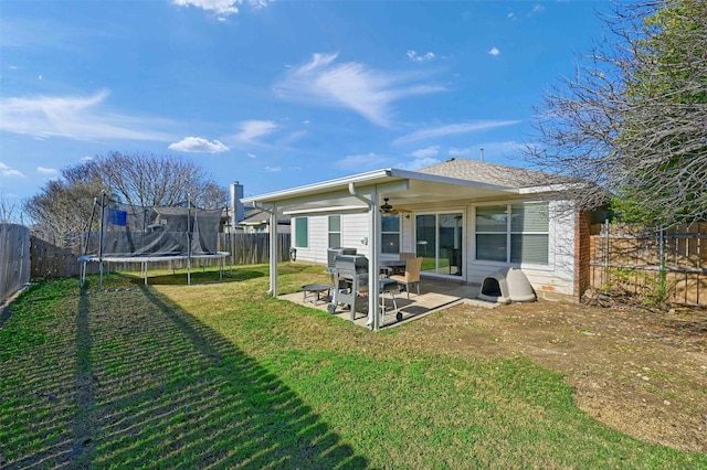 rear view of house with a lawn, a patio area, and a trampoline