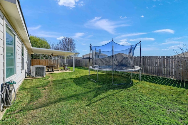 view of yard featuring a trampoline and central air condition unit