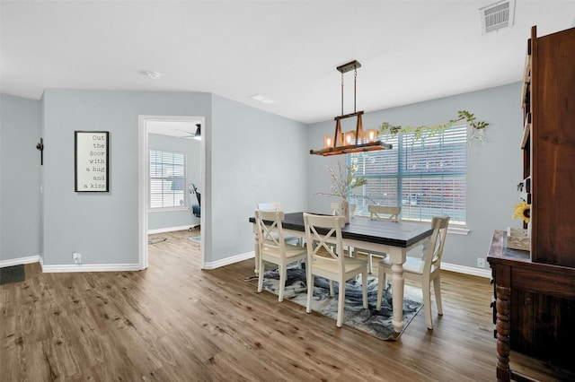 dining area with ceiling fan with notable chandelier and wood-type flooring