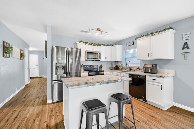 kitchen with black appliances, a center island, white cabinets, and sink