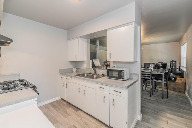 kitchen with white cabinetry, sink, range hood, and light hardwood / wood-style flooring