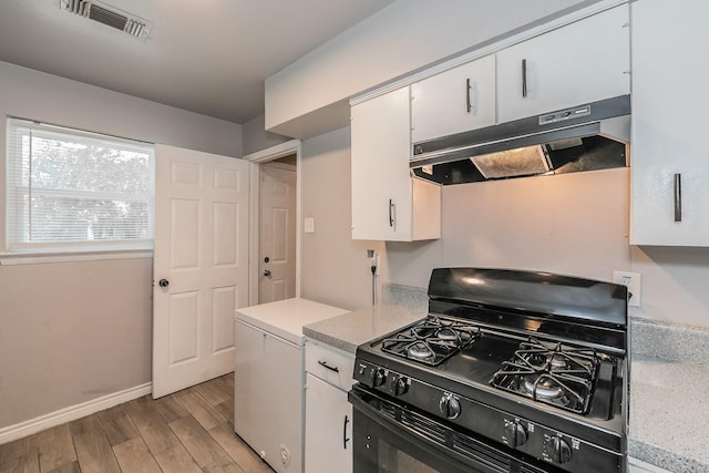 kitchen with black gas range, white cabinets, and fridge