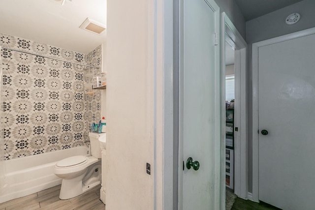 bathroom with tiled shower / bath, wood-type flooring, and toilet