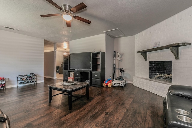 living room featuring ceiling fan, a fireplace, dark hardwood / wood-style floors, and a textured ceiling