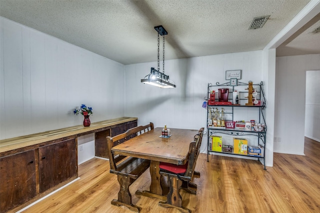 dining space with light hardwood / wood-style floors and a textured ceiling