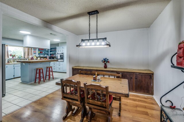 dining space featuring light wood-type flooring and a textured ceiling