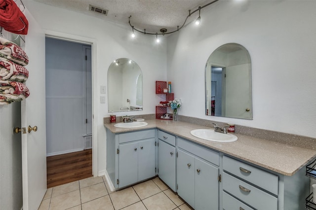 bathroom featuring vanity, rail lighting, tile patterned flooring, and a textured ceiling