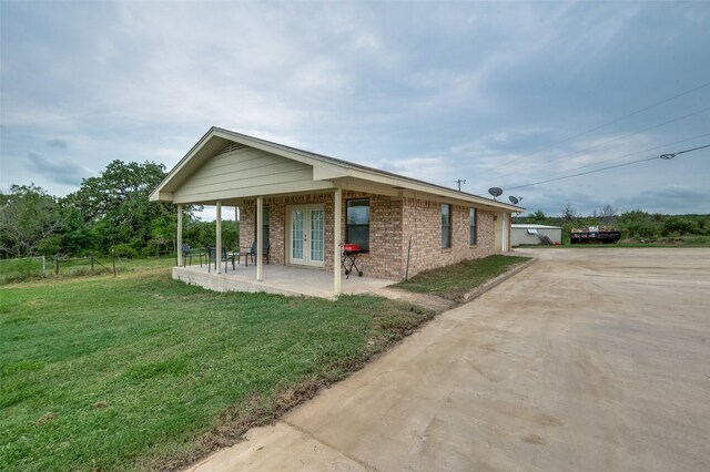 view of home's exterior with a porch, a yard, and french doors