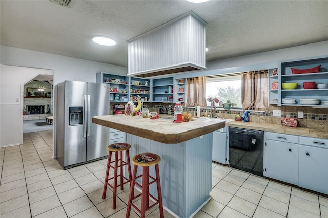 kitchen with stainless steel fridge, tasteful backsplash, a textured ceiling, dishwasher, and a center island