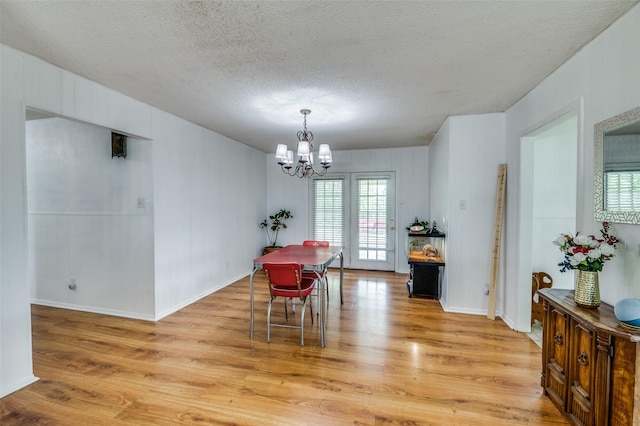 dining room with a textured ceiling, an inviting chandelier, and light hardwood / wood-style flooring