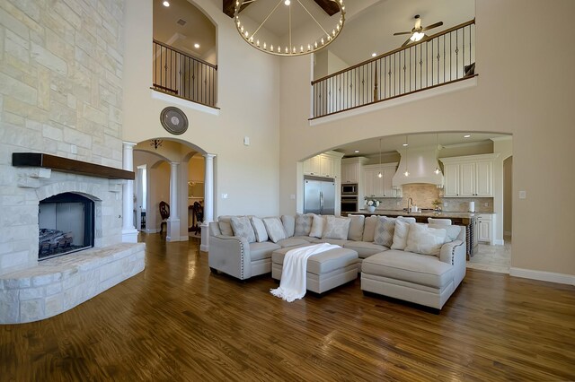 living room with ceiling fan, beam ceiling, a fireplace, and a high ceiling