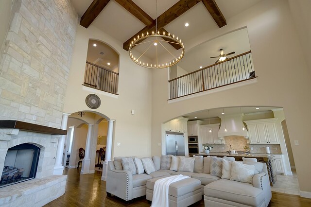 living room featuring a high ceiling, ornate columns, ceiling fan, and dark wood-type flooring