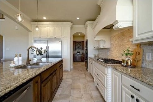 kitchen featuring backsplash, white cabinets, sink, appliances with stainless steel finishes, and decorative light fixtures