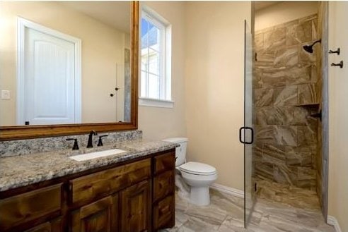 bathroom featuring vanity, toilet, an enclosed shower, and a healthy amount of sunlight