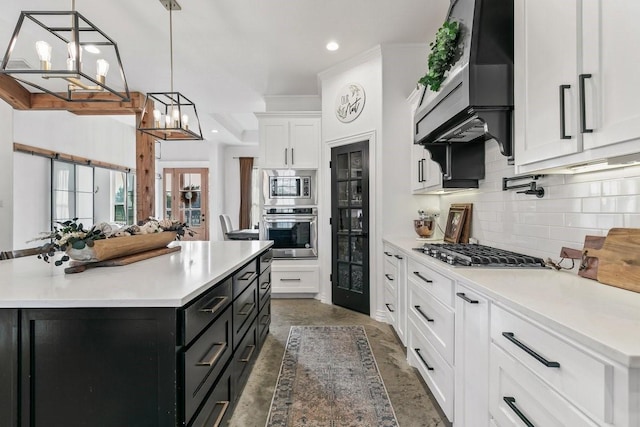 kitchen with appliances with stainless steel finishes, a center island, white cabinetry, and decorative light fixtures