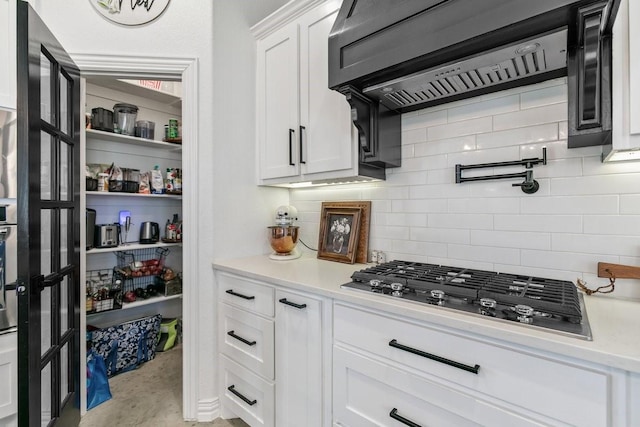 kitchen featuring custom exhaust hood, white cabinetry, backsplash, and black gas stovetop