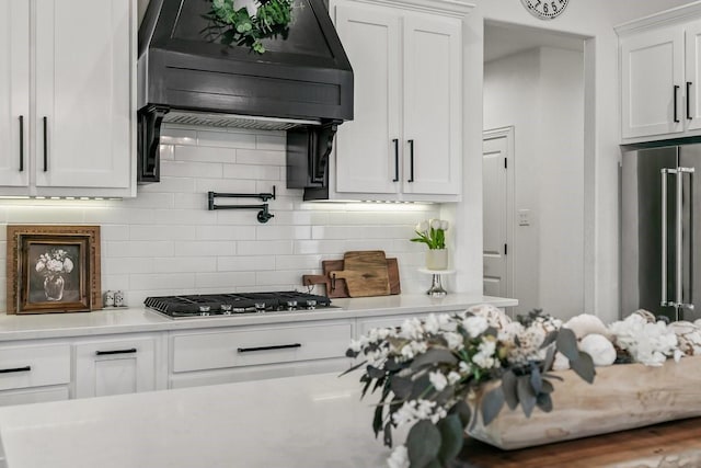 kitchen with white cabinets, stainless steel appliances, backsplash, and range hood