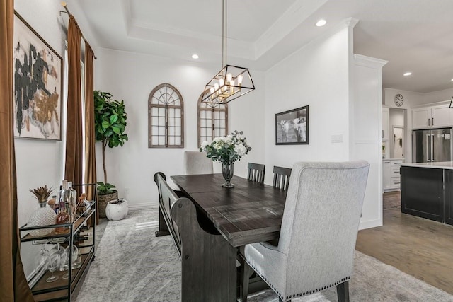 dining area with an inviting chandelier, a tray ceiling, and crown molding