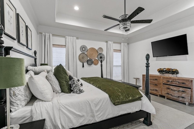 bedroom featuring ceiling fan, crown molding, multiple windows, and a tray ceiling