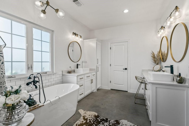 bathroom with vanity, concrete flooring, a healthy amount of sunlight, and a bath