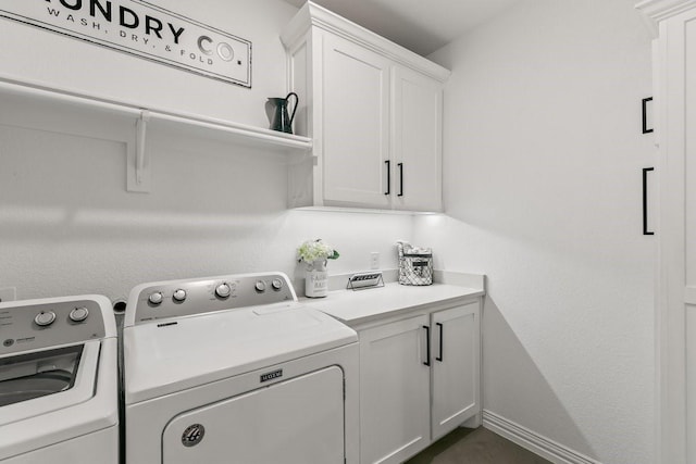 clothes washing area featuring separate washer and dryer and cabinets