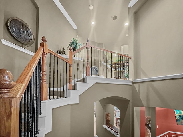 stairs featuring a towering ceiling and ornamental molding