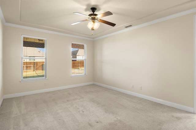 carpeted empty room with a tray ceiling, ceiling fan, and ornamental molding