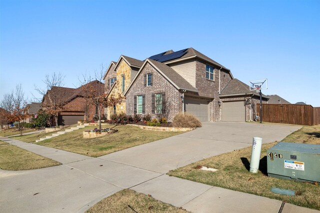 view of front of property featuring a front yard, solar panels, and a garage