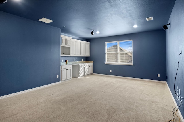 interior space with light carpet, white cabinets, and a textured ceiling