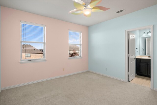 unfurnished bedroom featuring ensuite bathroom, ceiling fan, sink, and light carpet