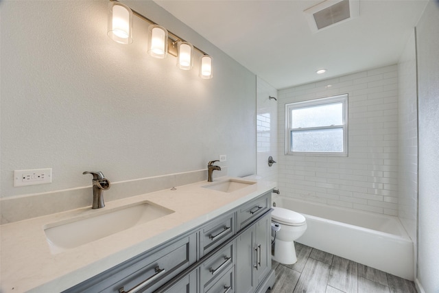 full bathroom with vanity, tiled shower / bath combo, and toilet