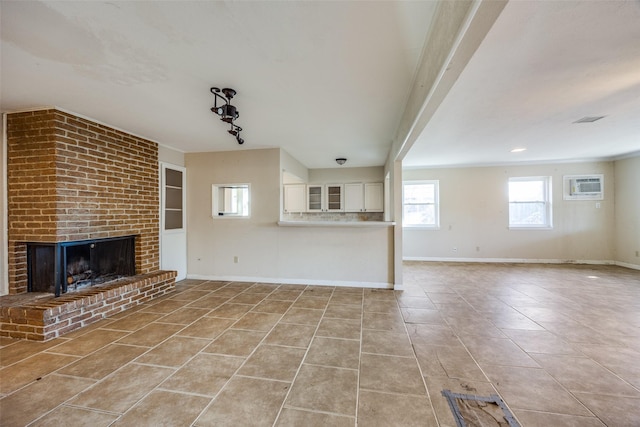 unfurnished living room featuring a fireplace, light tile patterned floors, and an AC wall unit