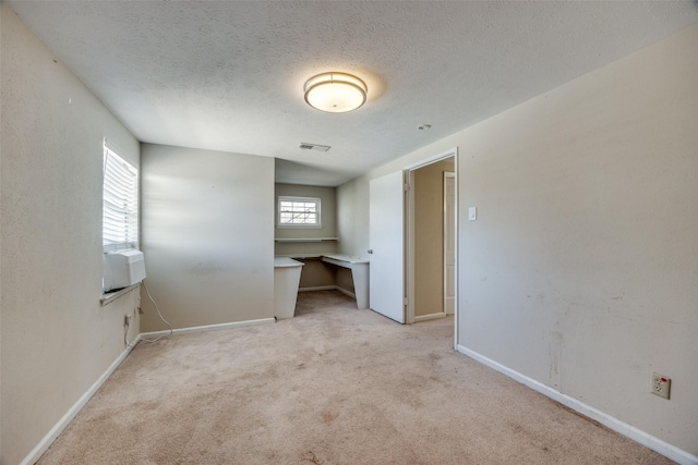 interior space featuring a textured ceiling, a healthy amount of sunlight, light carpet, and cooling unit