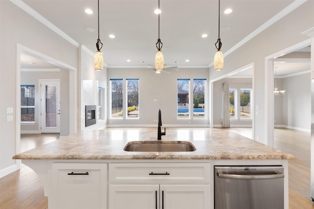 kitchen with open floor plan, light stone counters, ceiling fan, and a sink