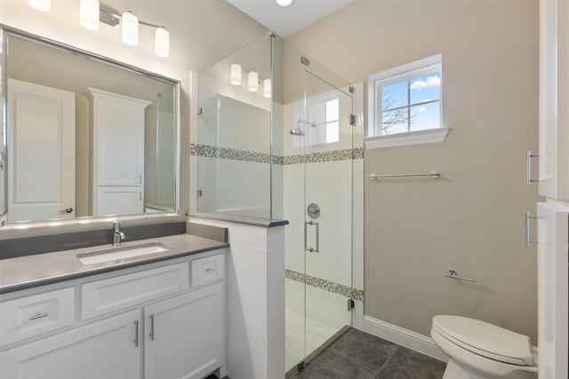 bathroom featuring baseboards, toilet, vanity, tile patterned flooring, and a stall shower