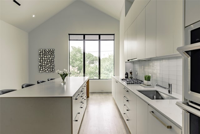 kitchen featuring a kitchen island, white cabinetry, tasteful backsplash, a kitchen breakfast bar, and vaulted ceiling