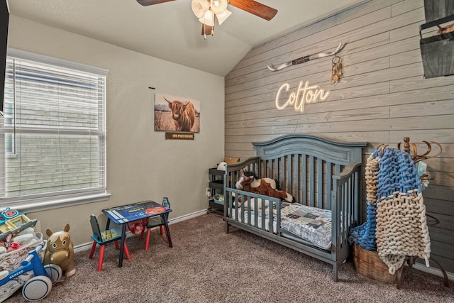 bedroom featuring multiple windows, ceiling fan, a nursery area, and wood walls