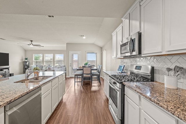 kitchen with white cabinets, stainless steel appliances, vaulted ceiling, and sink