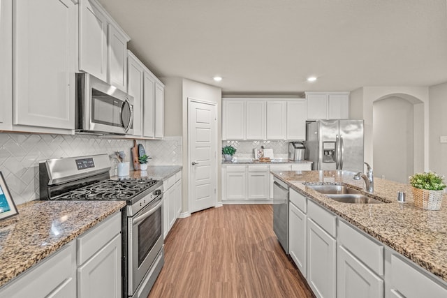 kitchen featuring appliances with stainless steel finishes, hardwood / wood-style flooring, white cabinetry, and sink